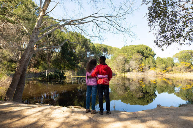 Счастливая разнообразная пара, стоящая на озере в сельской местности. здоровый, активный уличный образ жизни и досуг. — стоковое фото