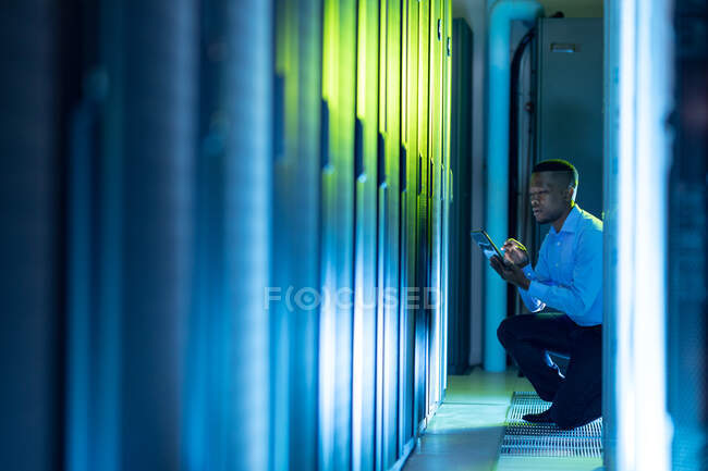 Tecnico informatico afroamericano di sesso maschile che utilizza tablet che lavora nella sala server. tecnologia digitale di memorizzazione delle informazioni e rete di comunicazione. — Foto stock