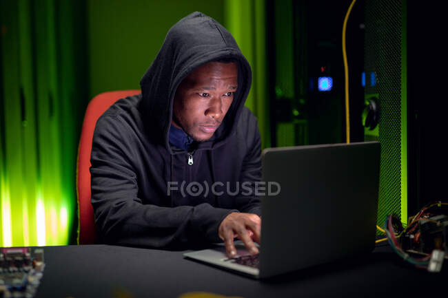 Afrikanischer Computertechniker mit Laptop, der im Serverraum für Unternehmen arbeitet. digitale Informationsspeicherung und Kommunikations-Netzwerktechnologie. — Stockfoto