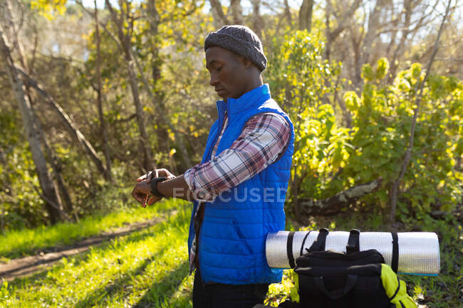 Homme afro-américain avec sac à dos randonnée dans la campagne. mode de vie sain et actif en plein air et temps libre. — Photo de stock