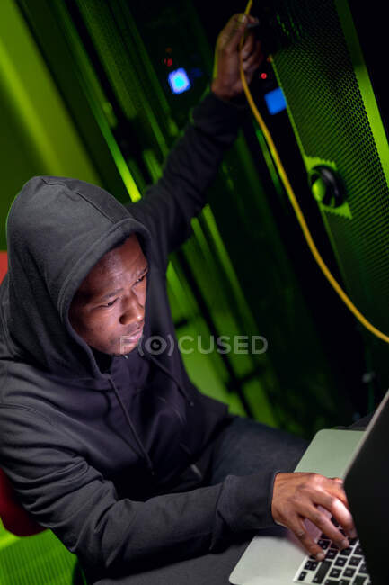 Afrikanischer Computertechniker mit Laptop, der im Serverraum für Unternehmen arbeitet. digitale Informationsspeicherung und Kommunikations-Netzwerktechnologie. — Stockfoto