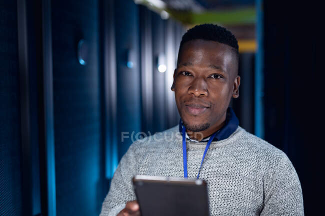 Technicien informatique afro-américain utilisant une tablette travaillant dans la salle des serveurs. stockage de l'information numérique et technologie des réseaux de communication. — Photo de stock