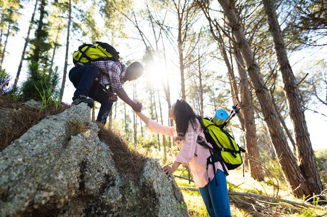 Feliz pareja diversa con mochilas de senderismo en el campo. estilo de vida al aire libre saludable y activo y tiempo libre. - foto de stock