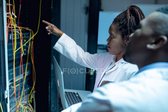 Afrikanische Computertechniker mit Laptop arbeiten im Serverraum. digitale Informationsspeicherung und Kommunikations-Netzwerktechnologie. — Stockfoto