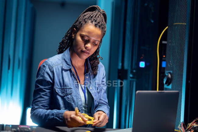 Técnica de informática afro-americana usando laptop trabalhando na sala de servidores. armazenamento digital de informações e tecnologia de rede de comunicação. — Fotografia de Stock