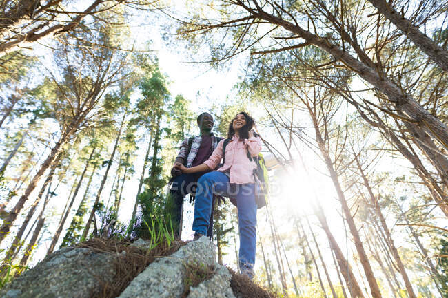 Happy diverse couple with backpacks hiking in countryside. healthy, active outdoor lifestyle and leisure time. — Stock Photo
