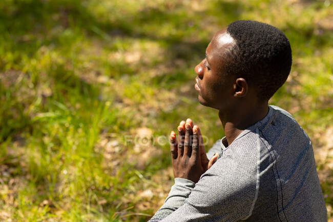 Расслабляющий африканский американец сидит и медитирует в сельской местности. здоровый, активный уличный образ жизни и досуг. — стоковое фото