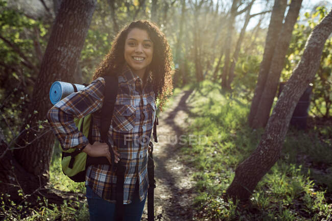 Mujer birracial feliz con mochila senderismo en el campo. estilo de vida al aire libre saludable y activo y tiempo libre. - foto de stock