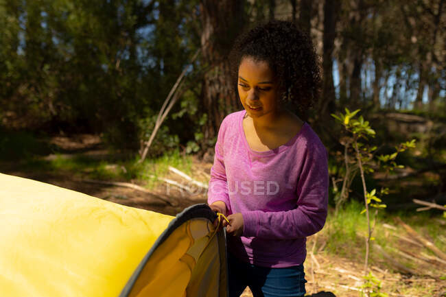 Biracial woman putting up the tent in countryside. healthy, active outdoor lifestyle and leisure time. — Stock Photo