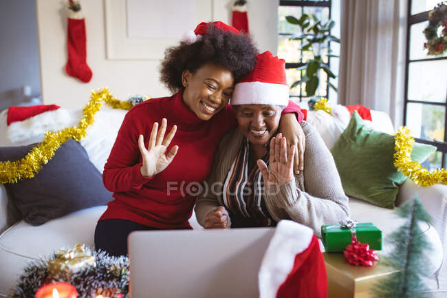 Feliz mulher idosa afro-americana e filha adulta em chapéus de Papai Noel fazendo videochamada de Natal. Natal, festividade e tecnologia de comunicação. — Fotografia de Stock