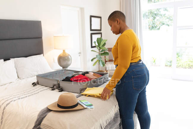 African american plus size woman packing suitcase for travel. travel preparation during covid 19 pandemic. — Stock Photo