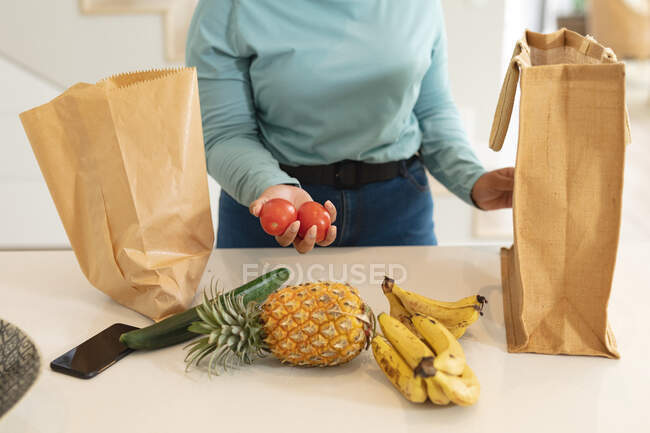 Midsection of plus size woman unpacking groceries in kitchen. lifestyle, cooking and spending time at home — Stock Photo