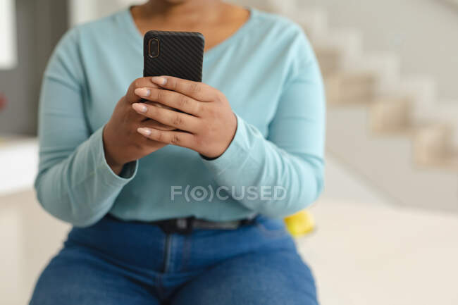 Середина африканского американец плюс размер женщина с видеозвонком на смартфоне на кухне. образ жизни, отдых, проведение времени дома с технологиями. — стоковое фото