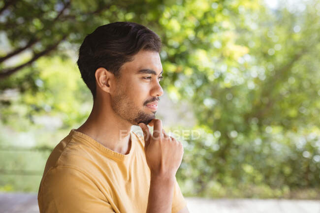 Улыбающийся двуличный мужчина трогает подбородок и думает в саду. проводить время дома в одиночестве. — стоковое фото