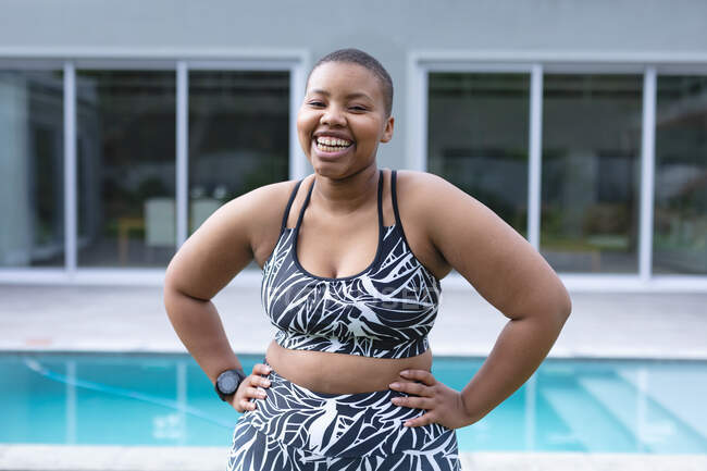 Feliz afroamericano más mujer de tamaño usando ropa deportiva y mirando a la cámara. fitness y estilo de vida saludable y activo. - foto de stock