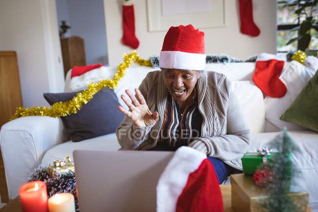Счастливая американка из Африки в шляпе Санты делает рождественский видеозвонок на ноутбук. Рождество, праздник и коммуникационные технологии. — стоковое фото