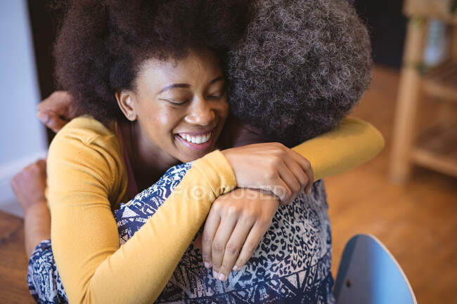 Donna anziana afroamericana con figlia adulta sorridente seduta e abbracciata. famiglia tempo a casa insieme. — Foto stock