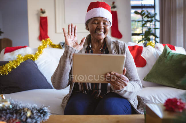 Feliz afro-americana idosa em santa chapéu fazendo tablet chamada de vídeo de Natal. Natal, festividade e tecnologia de comunicação. — Fotografia de Stock