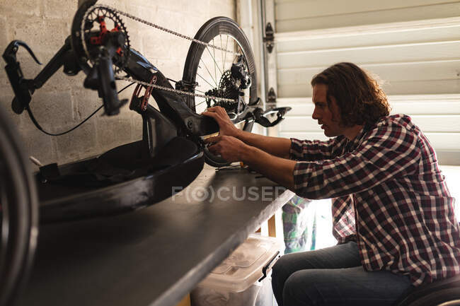 Caucasian disabled man sitting on wheelchair repairing another wheelchair at home. disability and handicap concept — Stock Photo