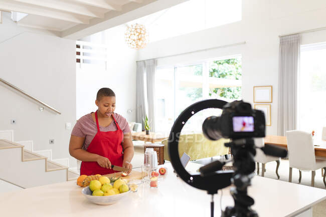 Африканський американець плюс жінка різання фруктів, робить vlog на кухні. спосіб життя, приготування їжі та перебування вдома. — стокове фото