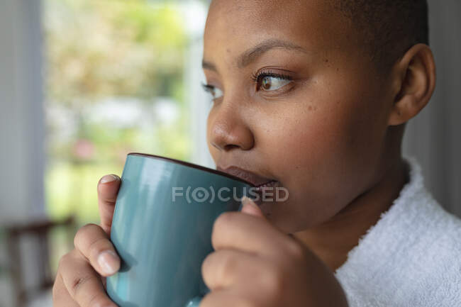 Расслабленный африканский американец плюс женщина размера пьет кофе дома. образ жизни, отдых и проведение времени дома. — стоковое фото