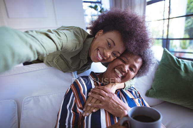 Portrait d'une femme âgée afro-américaine souriante avec sa fille adulte prenant du selfie. temps en famille à la maison ensemble. — Photo de stock