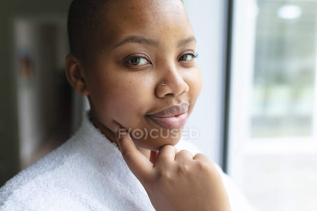 Ritratto di donna afroamericana plus size in piedi alla finestra e guardando la macchina fotografica. stile di vita, tempo libero e trascorrere del tempo a casa. — Foto stock