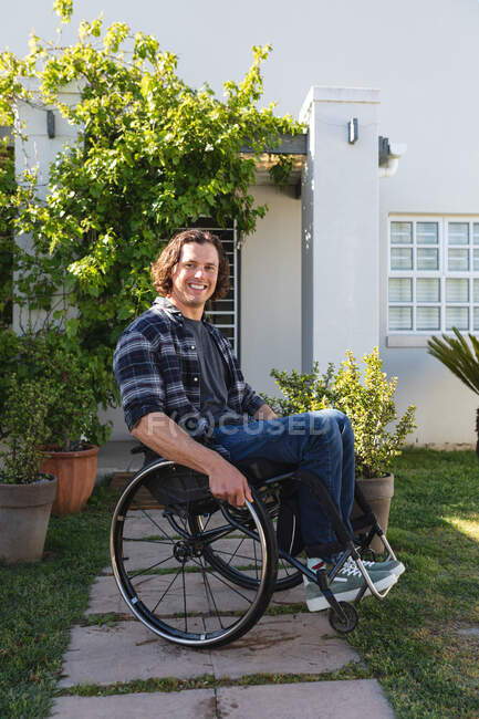 Portrait d'un homme handicapé caucasien assis en fauteuil roulant souriant dans le jardin. handicap et handicap concept — Photo de stock