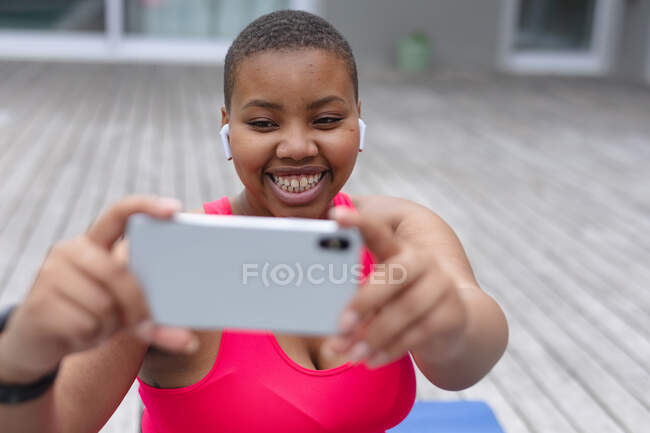 Heureuse femme afro-américaine plus de taille faisant de l'exercice à l'extérieur, prenant du selfie. forme physique et mode de vie sain et actif. — Photo de stock