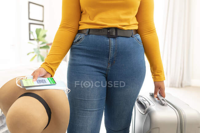 Midsection of plus size woman holding suitcase and hat. travel preparation during covid 19 pandemic. — Stock Photo