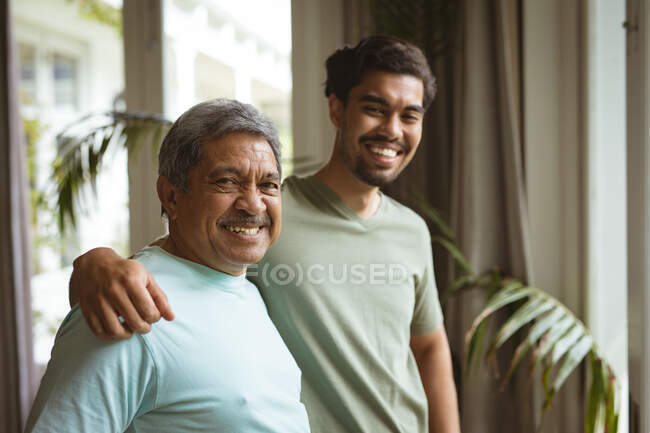 Портрет дорослого сина і старшого батька, який посміхається, дивиться на камеру і обіймає. сім 