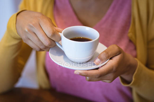 Großaufnahme einer Frau, die eine Tasse Kaffee in der Küche hält. Zeit allein zu Hause verbringen. — Stockfoto
