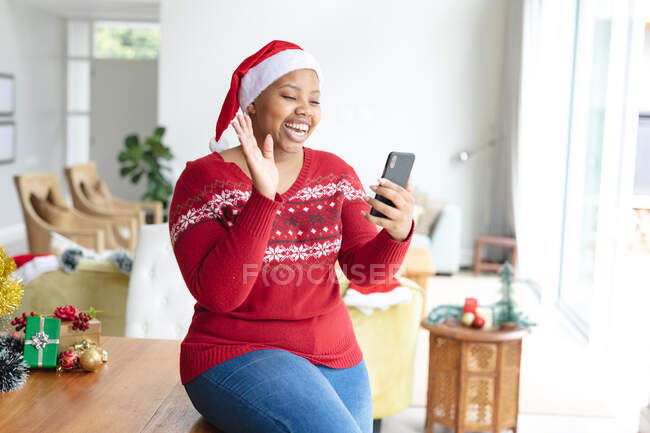 Felice afro americano plus size donna in cappello di Babbo Natale fare videochiamata di Natale su smartphone. Natale, festività e tecnologie di comunicazione. — Foto stock
