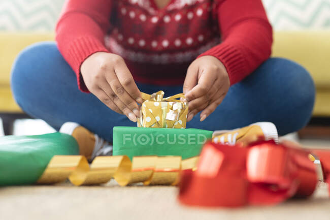 Sección media de mujer de talla grande en Santa Sombrero envolviendo regalos en casa. concepto de navidad, fiesta y tradición. - foto de stock