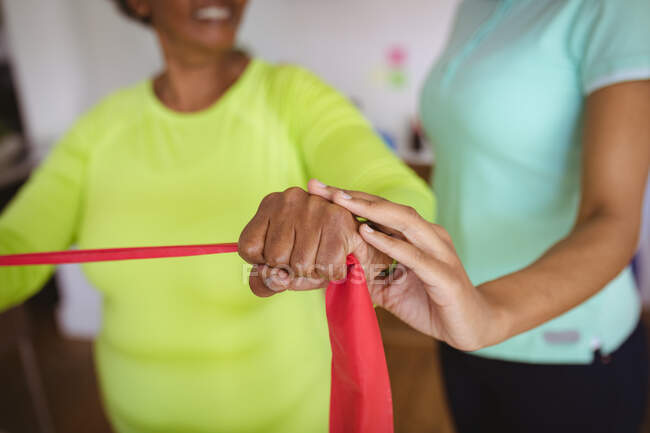 African american female physiotherapist treating arms of smiling senior female patient at clinic. senior healthcare and medical physiotherapy treatment. — Stock Photo