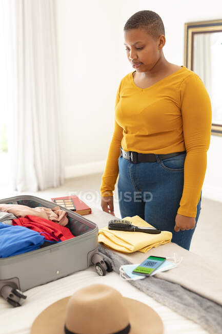 Africano americano plus tamanho mulher mala de embalagem para viagens. preparação de viagens durante a pandemia de 19 pessoas. — Fotografia de Stock