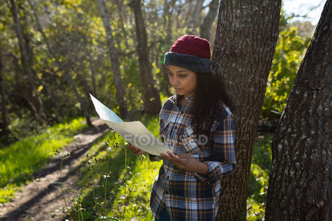 Happy biracial woman taking break from hiking in countryside. healthy, active outdoor lifestyle and leisure time. — Stock Photo