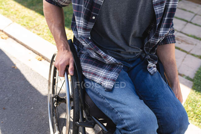 Sección media del hombre discapacitado sentado en silla de ruedas en la carretera. concepto de discapacidad y discapacidad - foto de stock
