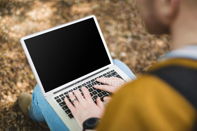 Albino-amerikanischer Mann sitzt mit Laptop im Park. digitaler Nomade unterwegs, unterwegs in der Stadt. — Stockfoto