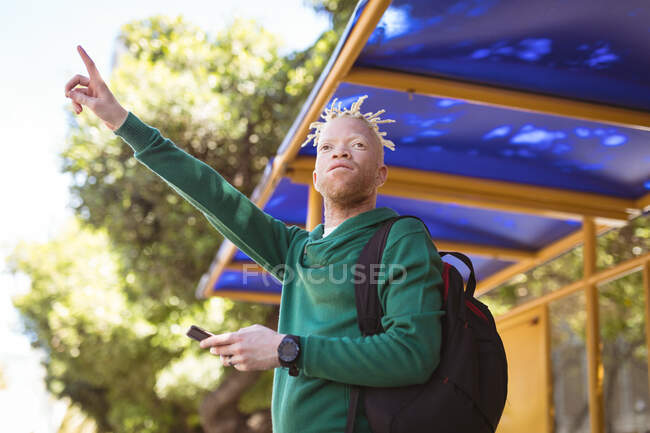 Африканский американец Альбинос с дредами машет смартфоном. цифровая реклама на ходу, на улице и по городу. — стоковое фото