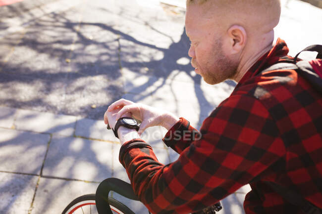 Réfléchi albinos homme afro-américain utilisant smartwatch. nomade numérique en déplacement, en déplacement dans la ville. — Photo de stock