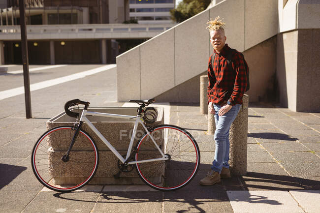 Retrato de homem americano albino africano sorridente com dreadlocks na rua com bicicleta. em movimento, fora e em torno da cidade. — Fotografia de Stock