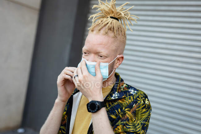 Homem americano africano albino com dreadlocks usando máscara facial. em movimento, para fora e sobre na cidade durante a pandemia covid 19. — Fotografia de Stock