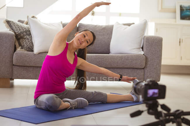 Glückliche asiatische Frau turnt auf Matte und macht fittnes vlog von zu Hause aus. gesunder aktiver Lebensstil und Fitness zu Hause mit Technologie. — Stockfoto