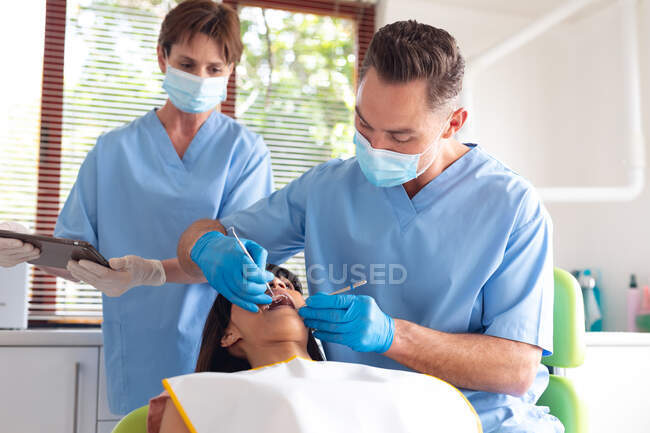 Dentista masculino caucasiano e enfermeira dentária feminina examinando os dentes do paciente na clínica odontológica moderna. serviços de saúde e odontologia. — Fotografia de Stock