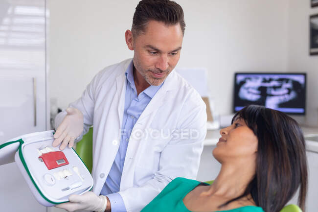 Lächelnder kaukasischer Zahnarzt, der die Zähne einer Patientin in einer modernen Zahnklinik untersucht. Gesundheits- und Zahnarztgeschäft. — Stockfoto