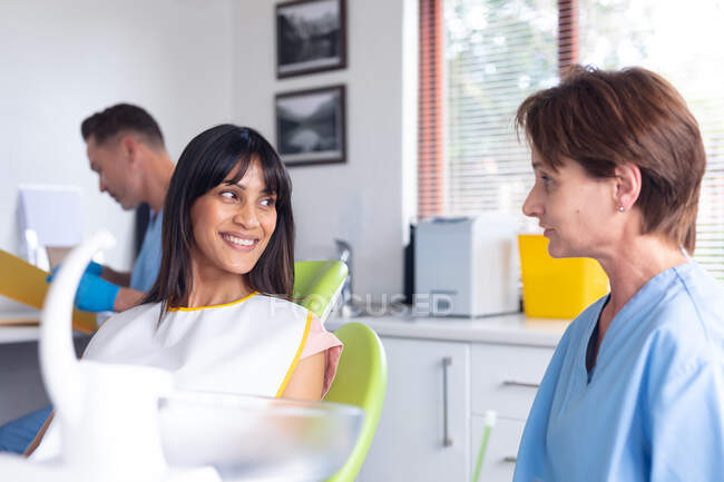 Caucasian female dental nurse talking to smiling female patient at modern dental clinic. healthcare and dentistry business. — Stock Photo