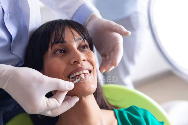 Кавказький самець-стоматолог вивчає зуби пацієнтки в сучасній стоматологічній клініці. Медичне обслуговування та стоматологія. — стокове фото