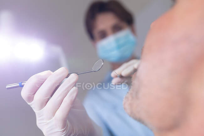 Infermiera odontoiatrica caucasica che esamina i denti di un paziente di sesso maschile in una moderna clinica dentale. attività sanitaria e odontoiatrica. — Foto stock