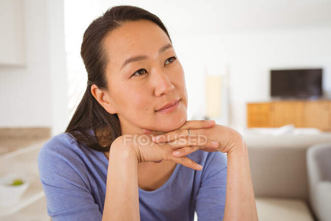 Retrato de mujer asiática pensativa sentada en el sofá en casa. estilo de vida, ocio y pasar tiempo en casa. - foto de stock